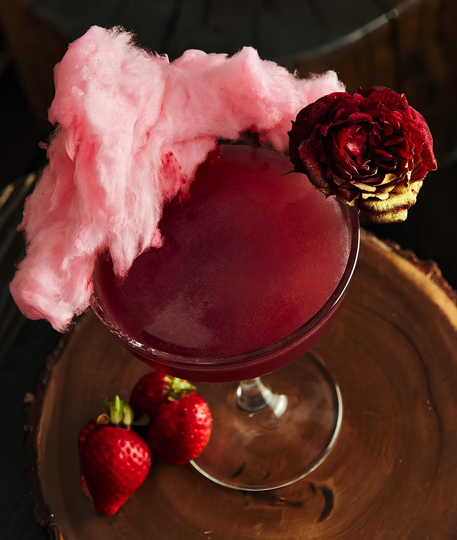 Cóctel rosa exclusivo con guarnición de algodón de azúcar en el bar galeón de Marbella